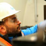 Close-up of a construction worker wearing safety gear while focusing on a task indoors.